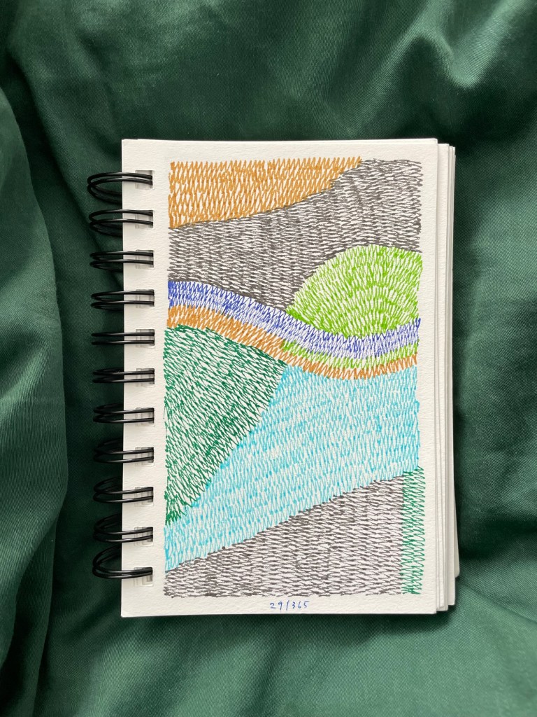 Wire bound sketchbook with line drawing on the open page, laying on top of green fabric