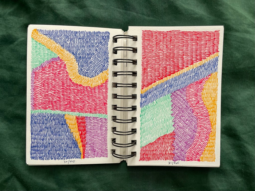 Wire bound sketchbook with line drawing on the open pages, laying on top of green fabric