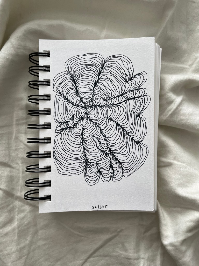 Wire bound sketchbook with line drawing on the open page, laying on top of white fabric