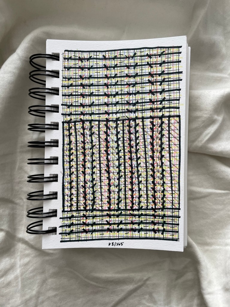 Wire bound sketchbook with line drawing on the open page, laying on top of white fabric