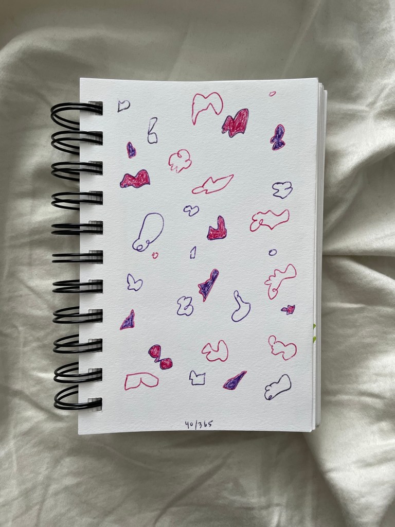 Wire bound sketchbook with line drawing on the open page, laying on top of white fabric