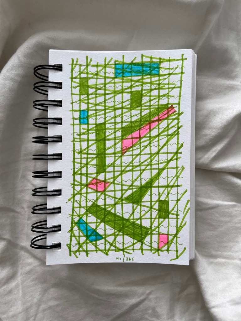 Wire bound sketchbook with line drawing on the open page, laying on top of white fabric