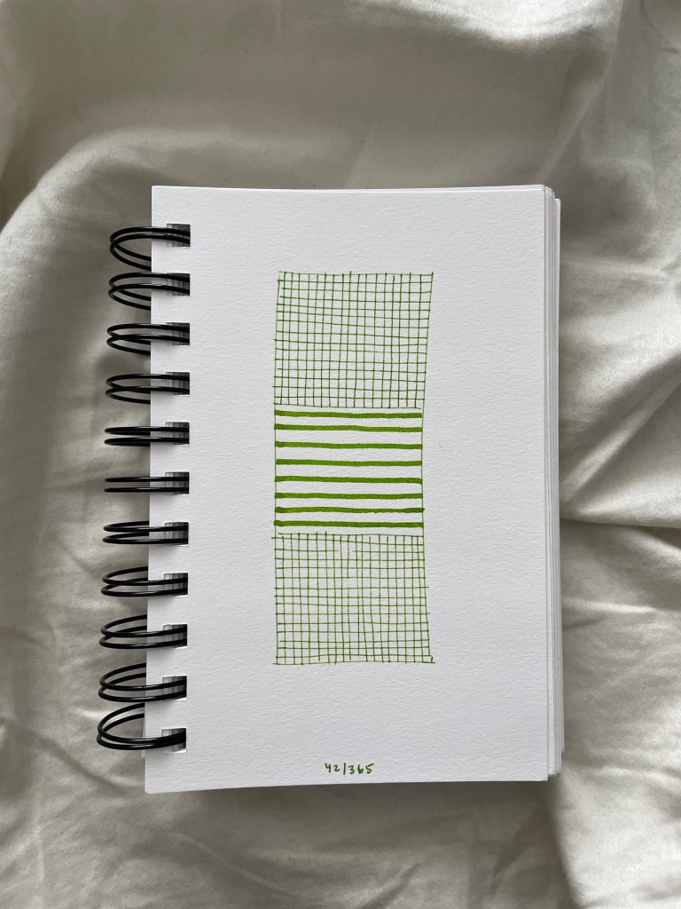 Wire bound sketchbook with line drawing on the open page, laying on top of white fabric